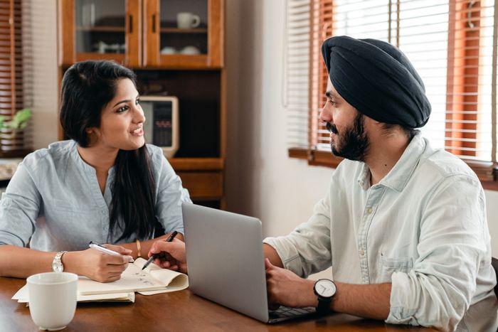 Two colleagues discussing work over a laptop at a table, smiling